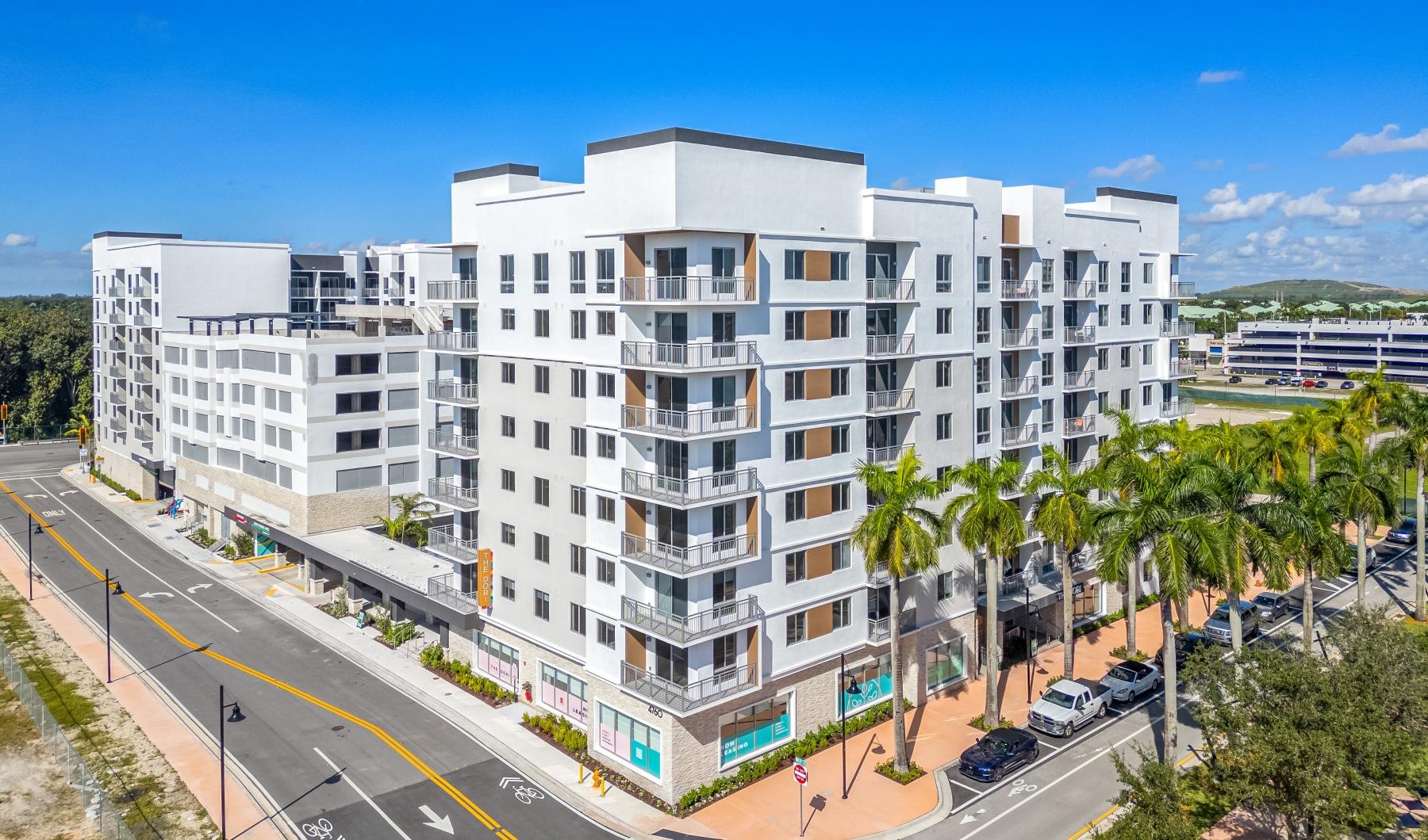 a building with palm trees and a road in front of it